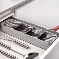 An empty, grey plastic cutlery tray with multiple compartments for kitchen drawer organisation.