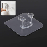 Transparent self-adhesive wall hook mounted on a clean, smooth wall.